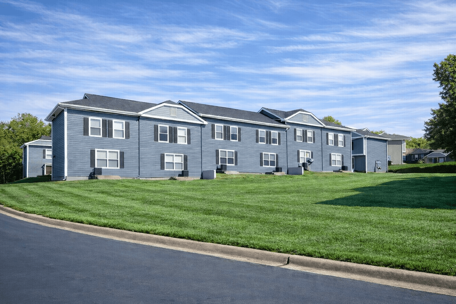 A row of houses with green lawns in front.